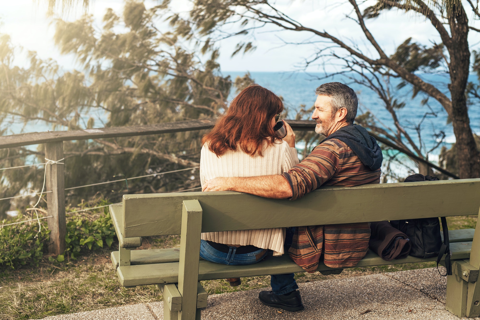 Middle-aged couple sitting on the bench in park and hugging